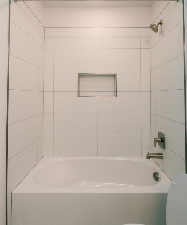 bathroom with tiled shower / bath combo and toilet