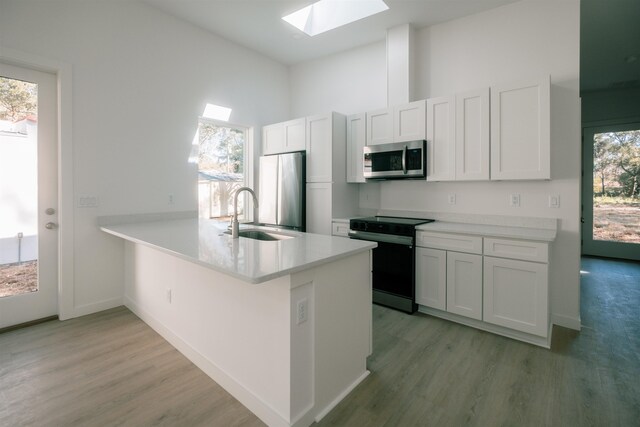 kitchen with appliances with stainless steel finishes, sink, white cabinets, and kitchen peninsula