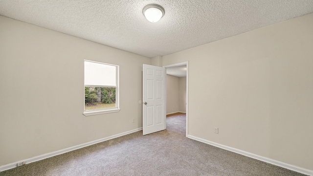 empty room featuring a textured ceiling, baseboards, and carpet flooring