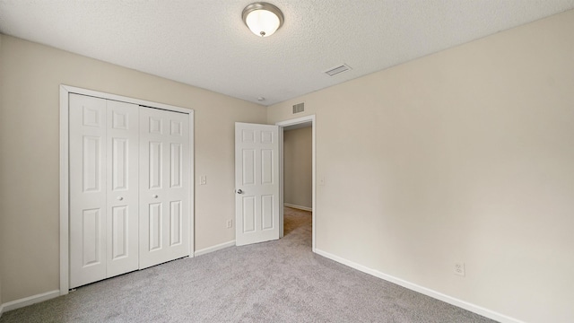 unfurnished bedroom with carpet floors, baseboards, visible vents, and a textured ceiling