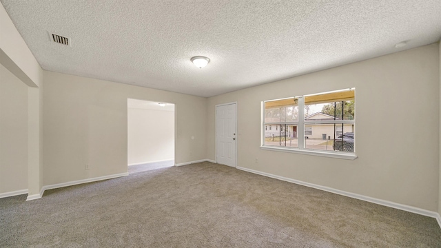 spare room with a textured ceiling, carpet, visible vents, and baseboards