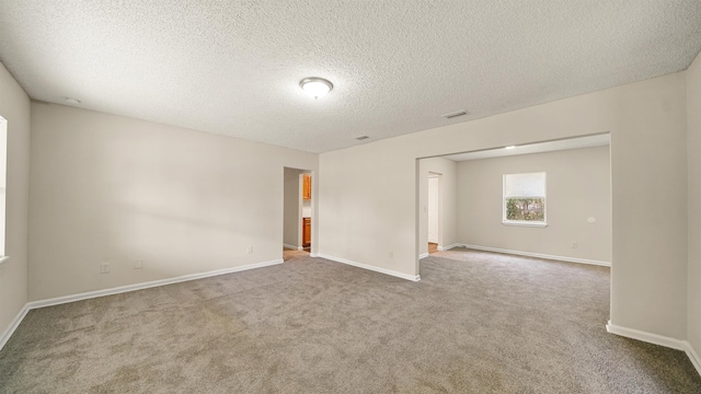 unfurnished room with carpet, baseboards, and a textured ceiling