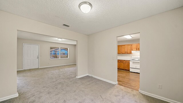 unfurnished room featuring light colored carpet, visible vents, and baseboards