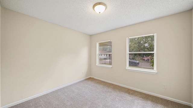 carpeted empty room featuring plenty of natural light, a textured ceiling, and baseboards