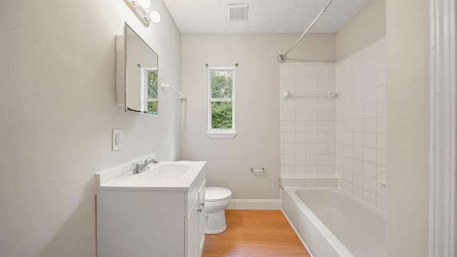 bathroom with visible vents, toilet, vanity, a textured ceiling, and wood finished floors