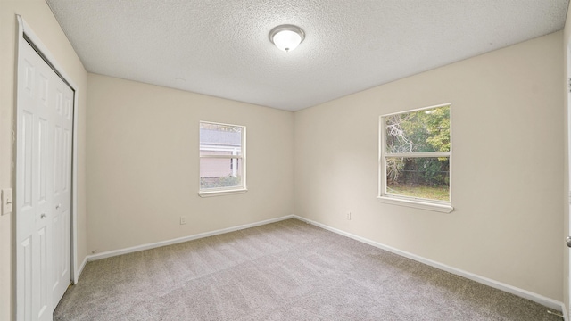 unfurnished bedroom featuring carpet floors, a closet, a textured ceiling, and baseboards