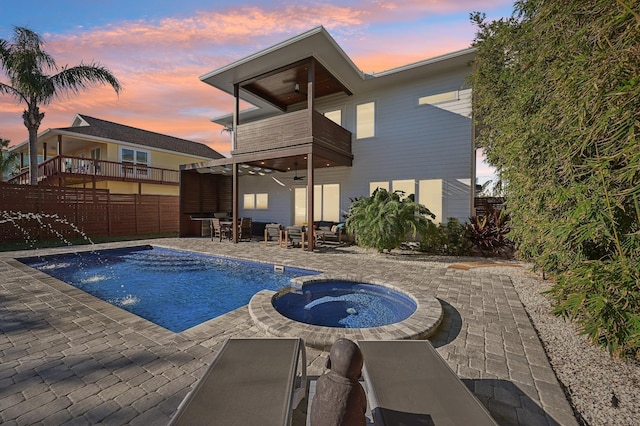 pool at dusk with a patio, ceiling fan, and an in ground hot tub