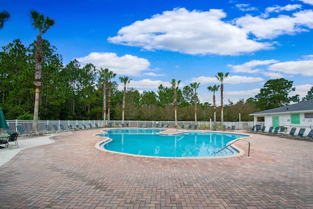 community pool featuring a patio and view of wooded area