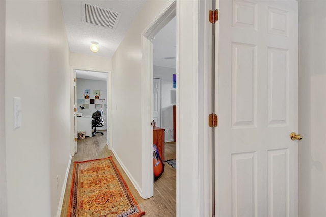 corridor featuring light wood-type flooring and baseboards