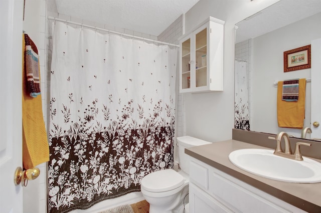 full bath featuring toilet, vanity, a textured ceiling, and curtained shower
