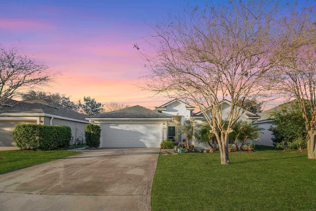 ranch-style house featuring concrete driveway, a lawn, a garage, and stucco siding