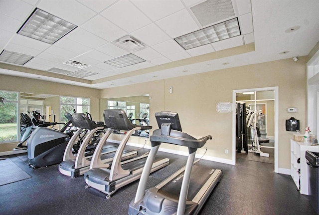 gym with baseboards, a tray ceiling, and a paneled ceiling