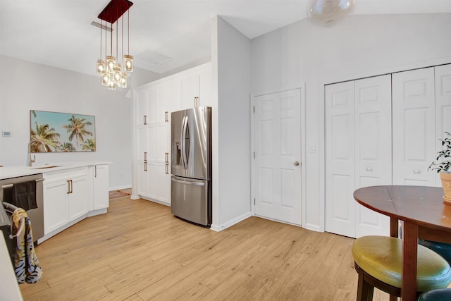 kitchen with stainless steel fridge, light wood finished floors, a sink, a chandelier, and white cabinetry