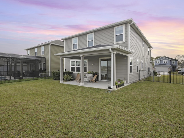 back house at dusk featuring a patio area and a yard