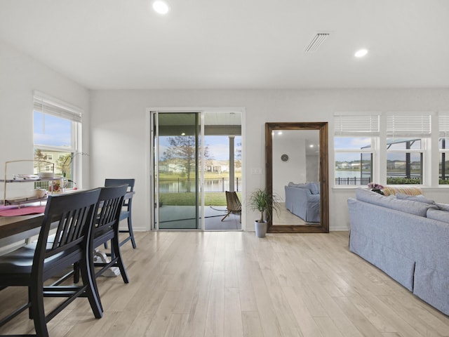 dining room with a water view, light hardwood / wood-style flooring, and plenty of natural light