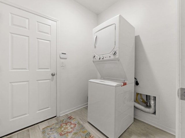 washroom with stacked washer and dryer and light hardwood / wood-style flooring