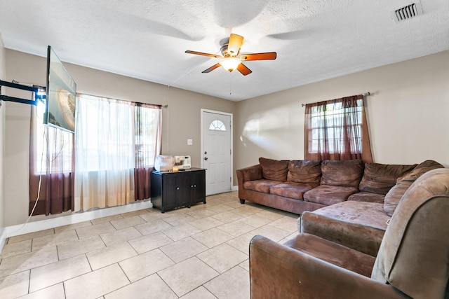 living room with ceiling fan, a textured ceiling, and light tile patterned floors