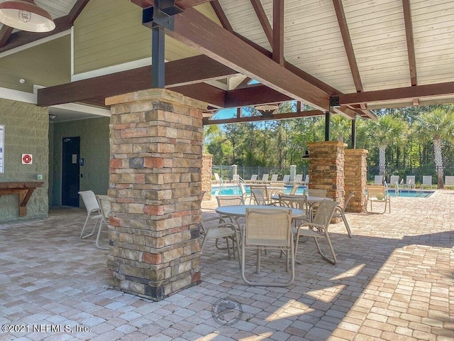 view of patio with outdoor dining area, a community pool, and fence