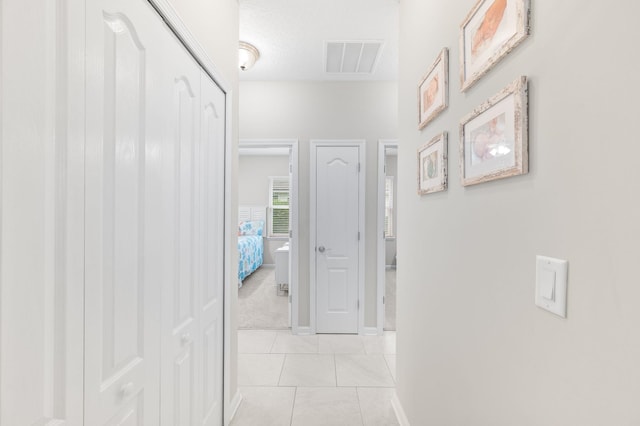 corridor with light tile patterned flooring, baseboards, and visible vents