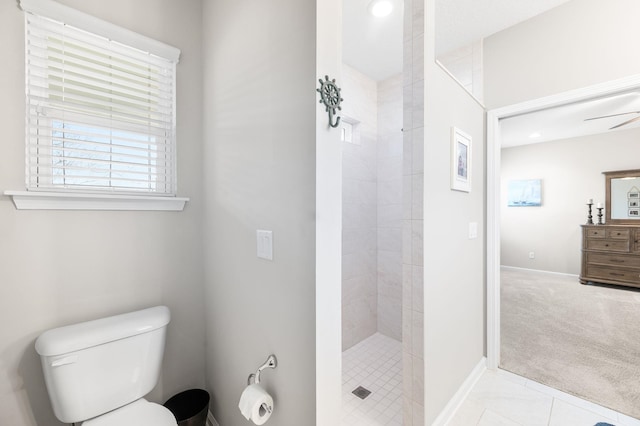 bathroom featuring a tile shower, tile patterned flooring, toilet, and baseboards