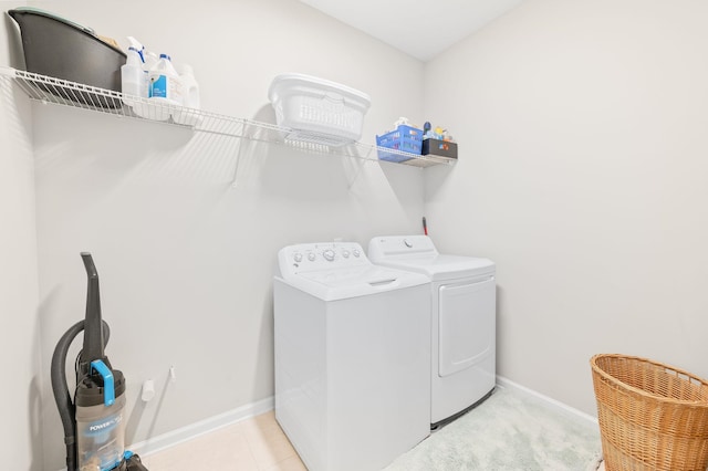 laundry area with laundry area, light tile patterned floors, separate washer and dryer, and baseboards