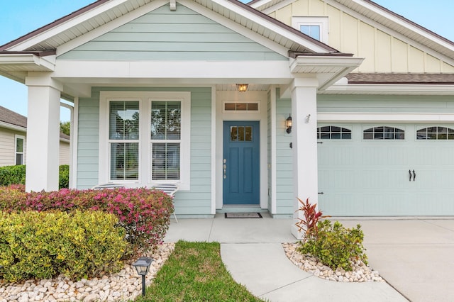 view of exterior entry with board and batten siding, concrete driveway, and a garage