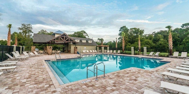 community pool with a patio area and fence