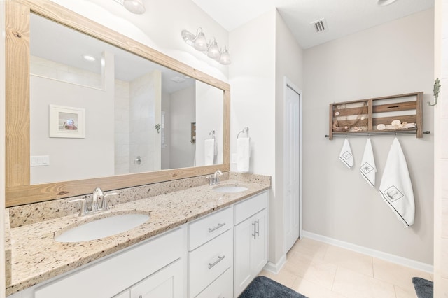 bathroom with double vanity, visible vents, tiled shower, and a sink