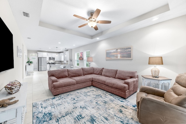 living area featuring a raised ceiling, light tile patterned floors, recessed lighting, and visible vents