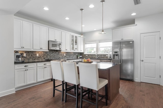 19 Smiling Fish Ln, Palm Coast, FL 32137 - kitchen featuring stainless steel fridge with ice dispenser, white microwave, tasteful backsplash, a kitchen island, and recessed lighting