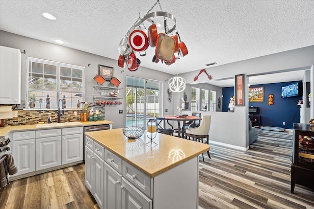 kitchen featuring white cabinets, decorative light fixtures, a center island, and sink