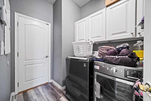 clothes washing area featuring cabinets, a textured ceiling, dark hardwood / wood-style flooring, and washing machine and clothes dryer