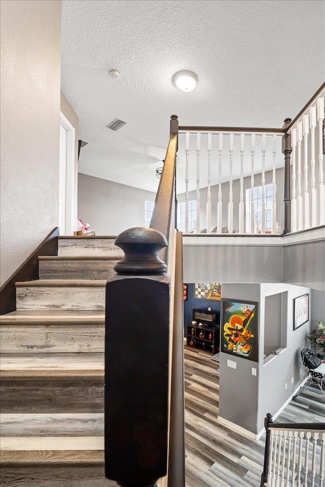 staircase with hardwood / wood-style floors and a textured ceiling