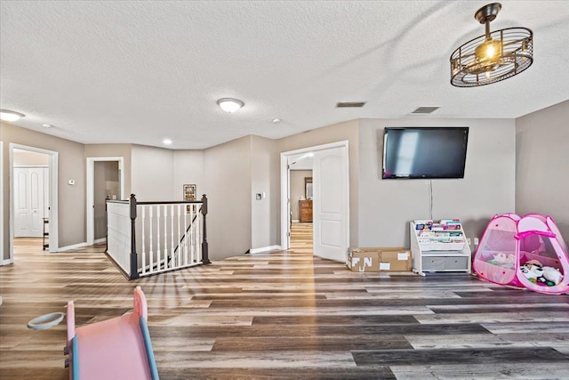 recreation room featuring a textured ceiling and hardwood / wood-style flooring