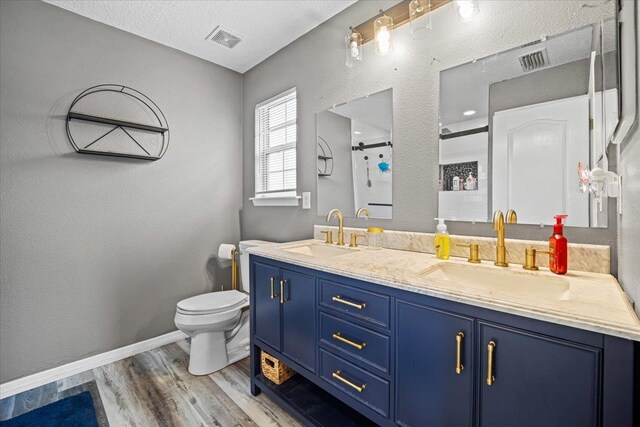 bathroom featuring a shower, a textured ceiling, toilet, vanity, and hardwood / wood-style flooring