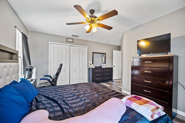 bedroom featuring dark hardwood / wood-style floors, ceiling fan, a textured ceiling, and a closet