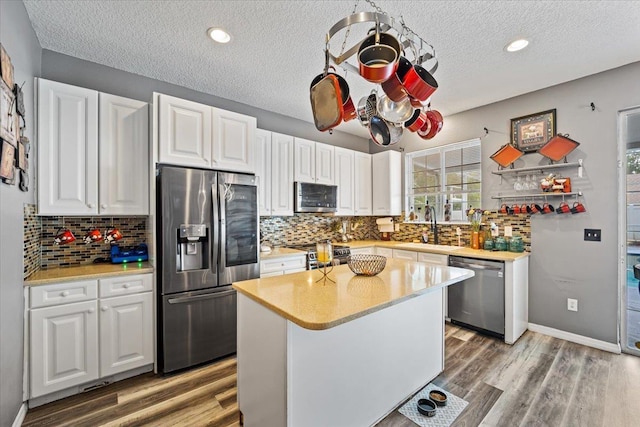 kitchen with white cabinetry, sink, wood-type flooring, a textured ceiling, and appliances with stainless steel finishes