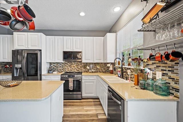 kitchen with white cabinets, a textured ceiling, stainless steel appliances, and sink