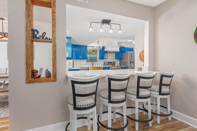 13 Douglas Ave, Saint Augustine, FL 32084 - kitchen featuring blue cabinets, stainless steel appliances, tasteful backsplash, and a peninsula