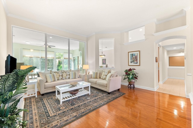 living room with arched walkways, baseboards, a ceiling fan, and wood finished floors