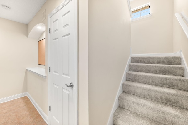 stairs with baseboards, tile patterned floors, and visible vents