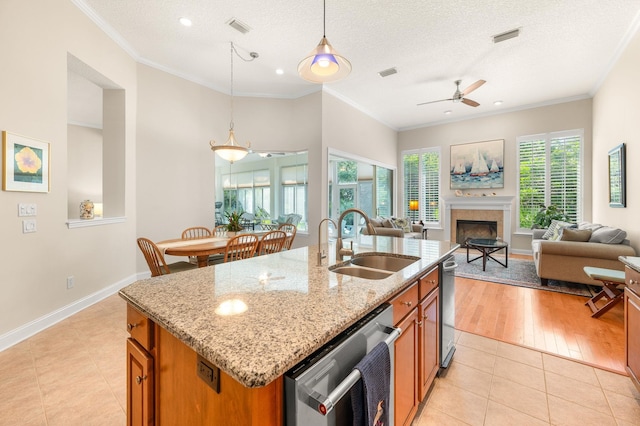 kitchen featuring light tile patterned floors, open floor plan, brown cabinetry, and a sink