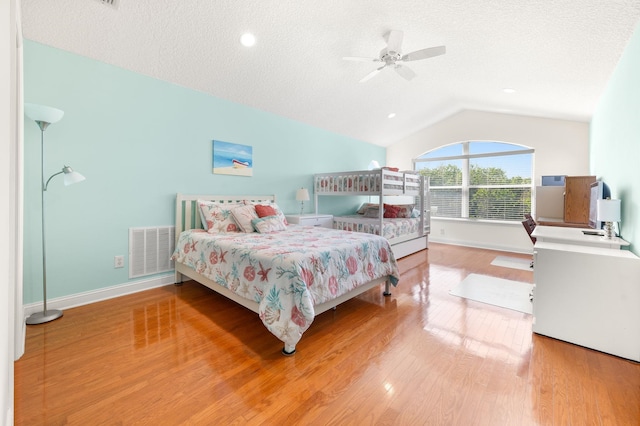 bedroom with a ceiling fan, a textured ceiling, visible vents, wood finished floors, and lofted ceiling