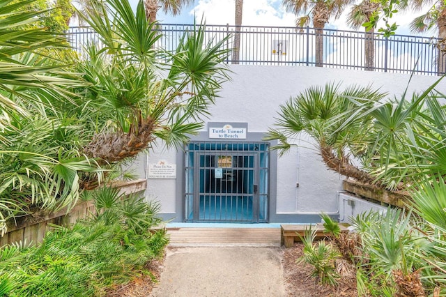 entrance to property featuring fence and stucco siding