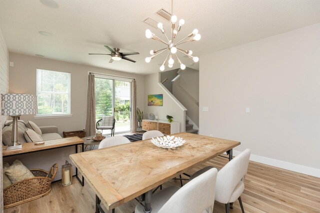 dining room with ceiling fan with notable chandelier and light hardwood / wood-style flooring