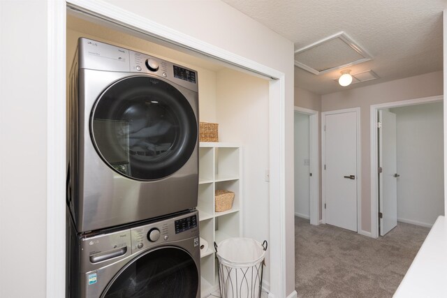 clothes washing area with a textured ceiling, light carpet, and stacked washer / drying machine