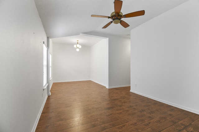 unfurnished room featuring ceiling fan with notable chandelier, dark hardwood / wood-style flooring, and vaulted ceiling