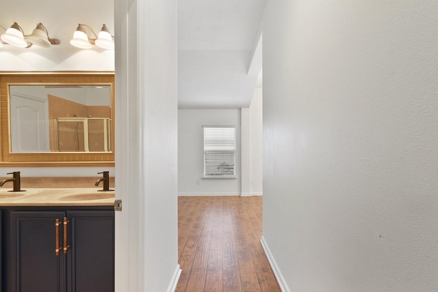 corridor featuring wood-type flooring and sink