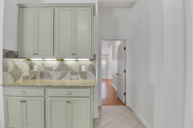 kitchen featuring light tile patterned flooring, light stone counters, and tasteful backsplash