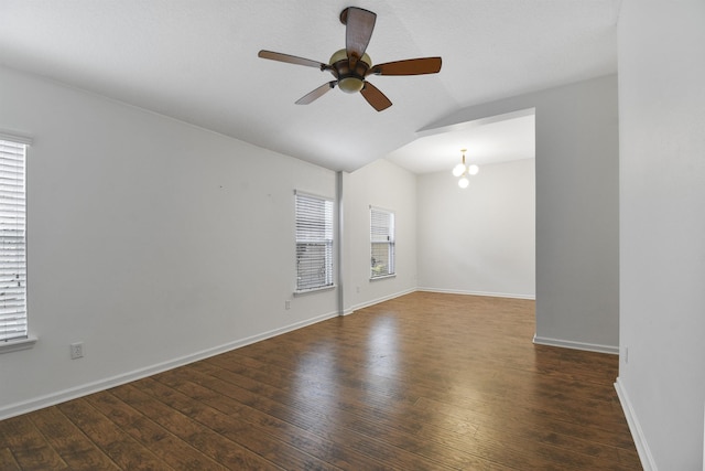 unfurnished room featuring vaulted ceiling, ceiling fan with notable chandelier, a healthy amount of sunlight, and dark hardwood / wood-style floors